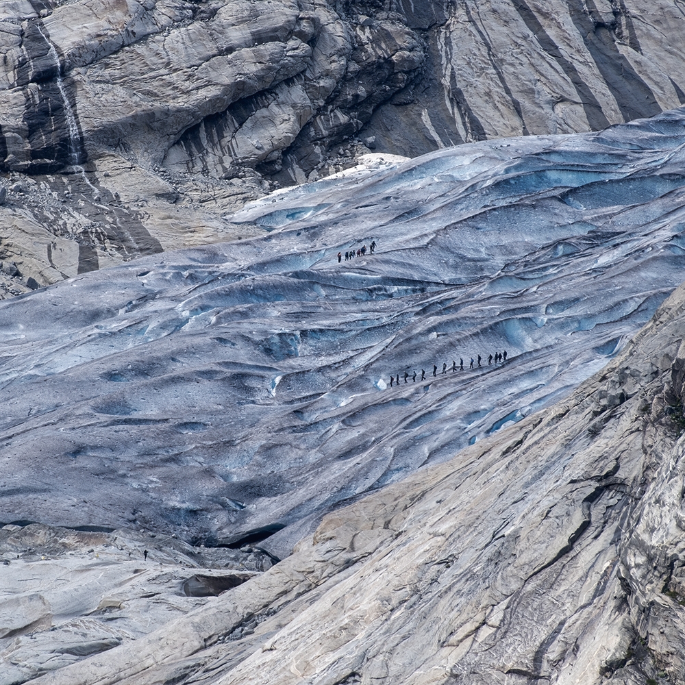 Mensen – op het oog bijna zo klein als mieren – lopen over het ijs van de Nigardsbreen, Jostedal, Noorwegen.